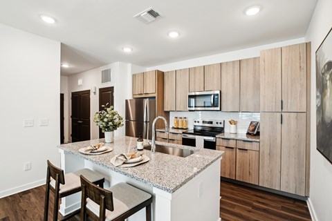 A kitchen with a table set for two and a refrigerator to the left.