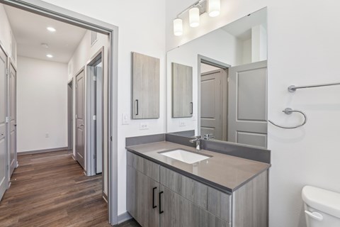 A bathroom with a sink, mirror, and toilet. at The Junction at Rockledge Apartments, Rockledge, Florida