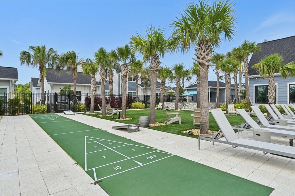 A tennis court is surrounded by palm trees and lounge chairs. at The Sophia, Venice, FL, 34275