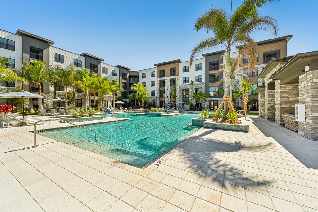 A swimming pool surrounded by palm trees and buildings at The Concord Luxury Apartments, Florida, 34240