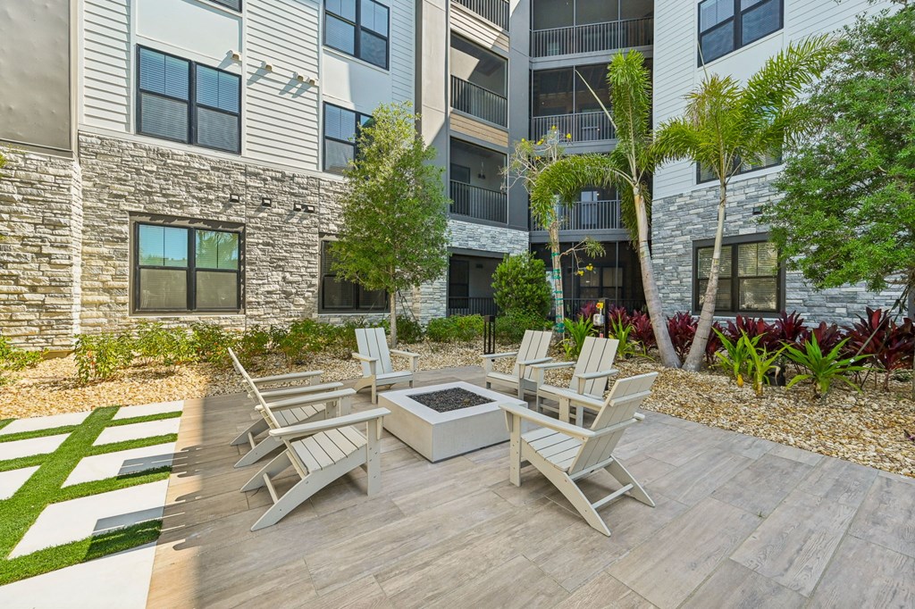 A patio with a table and chairs is surrounded by a garden and a building. at The Concord Luxury Apartments, Sarasota, FL, 34240