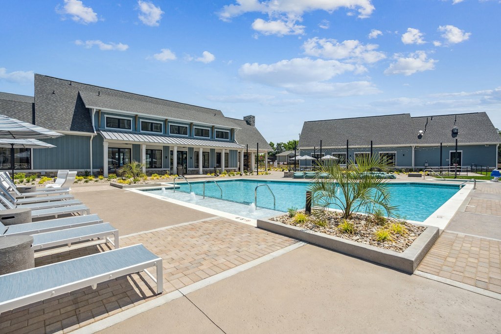 a swimming pool with lounge chairs and umbrellas in front of a building  at Taylor Farms, Charlotte