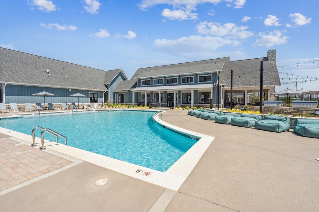 a large swimming pool with lounge chairs and umbrellas in front of a building  at Taylor Farms, Charlotte, 28262