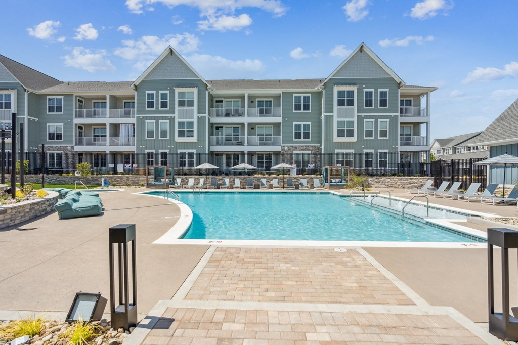 a large swimming pool with tanning deck chairs and umbrellas in front of an apartment  at Taylor Farms, Charlotte, 28262