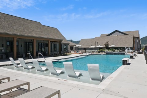 A pool with chairs and a building in the background.