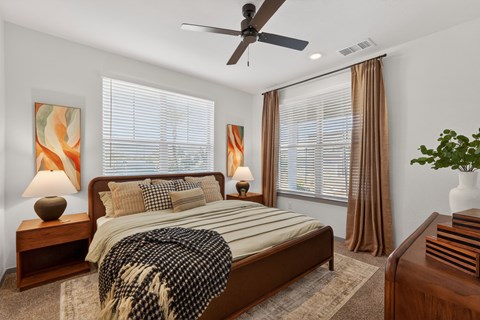 A bedroom with a bed, nightstands, and a ceiling fan.