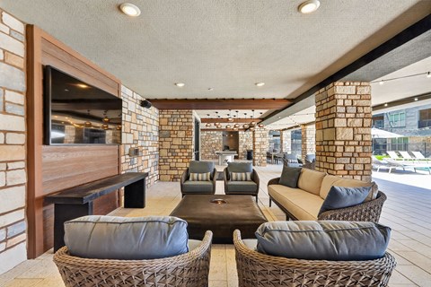 A modern outdoor seating area with a stone wall and wicker furniture.