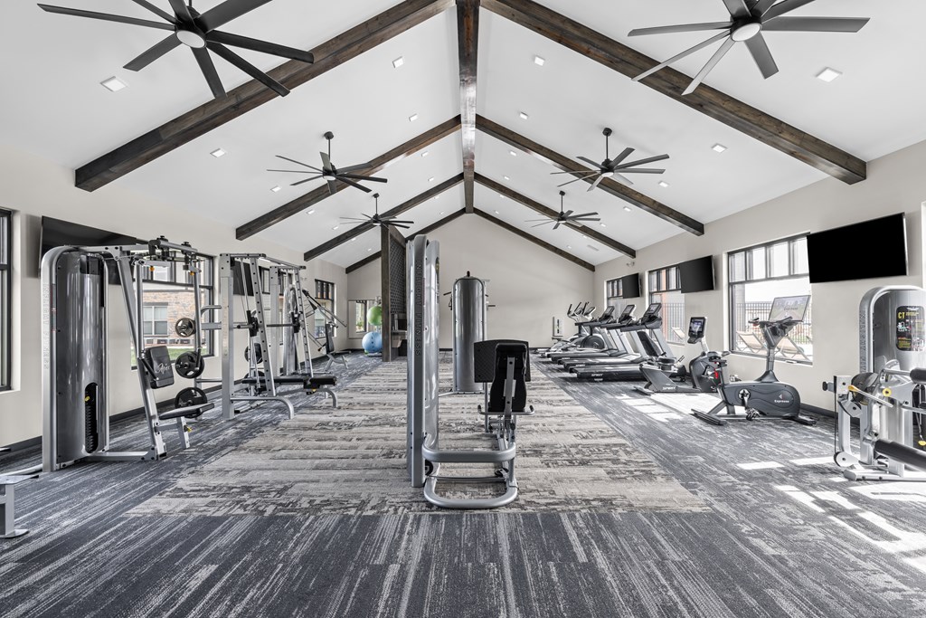 a gym with weights and cardio machines and ceiling fans