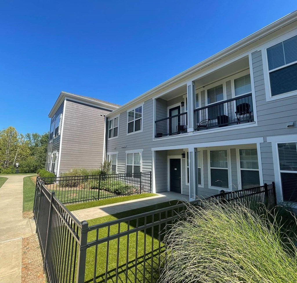 an apartment building with a grassy yard and a black fence