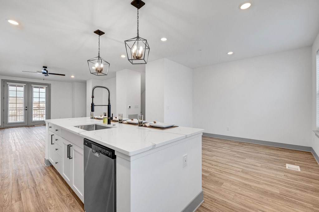 a large white kitchen with a large island and two hanging lights at Meridian at CityPlace, Woodbury Minnesota