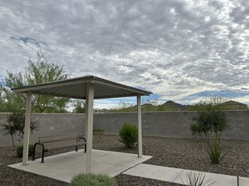a park bench under a pavilion with a cloudy sky