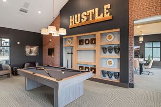 a pool table in the lobby of a building with a hustle sign