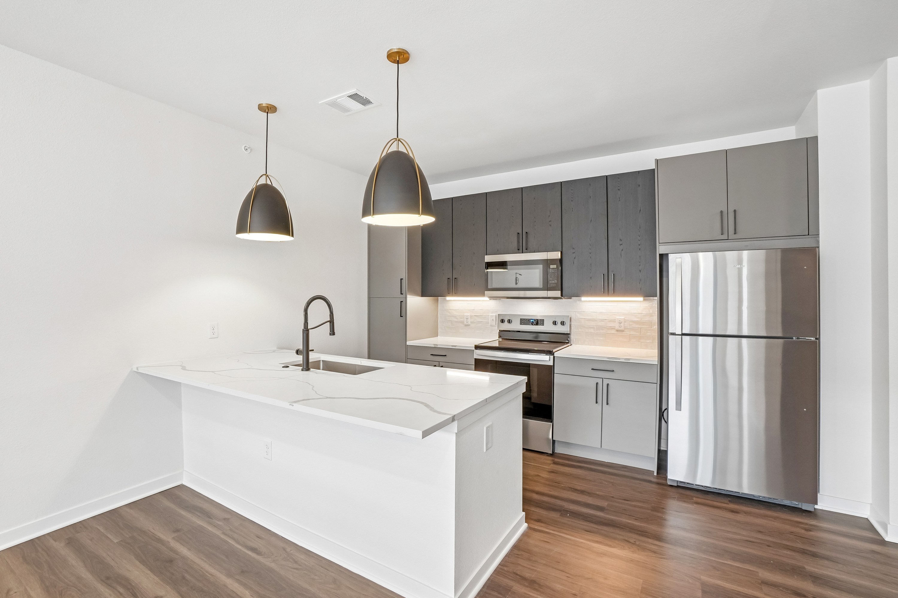 A modern kitchen with a white island and stainless steel appliances.