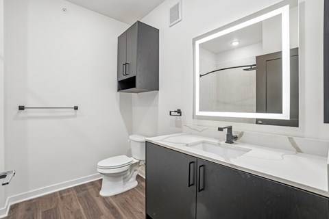 A bathroom with a toilet, sink, and mirror.