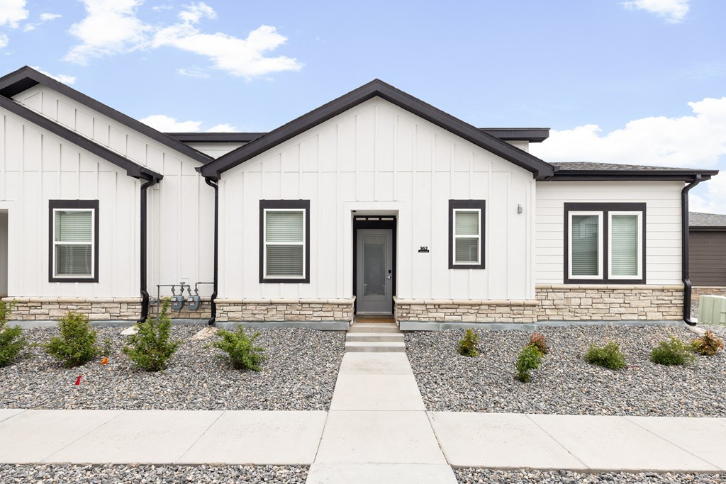 the front of a white home with a sidewalk in front of it