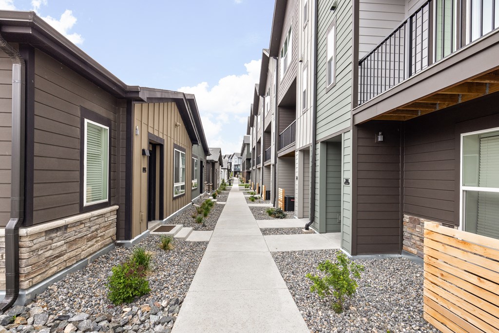 an empty sidewalk between two rows of houses