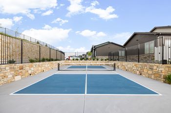a blue tennis court in the backyard of a house with a fence