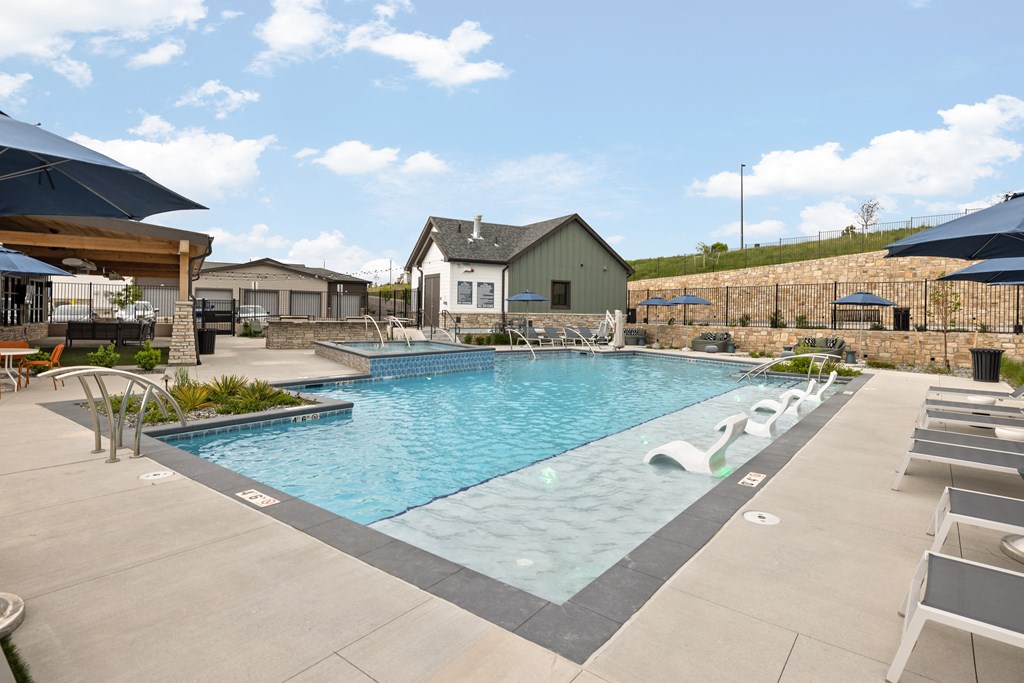 a swimming pool with chairs and umbrellas at the resort on a sunny day