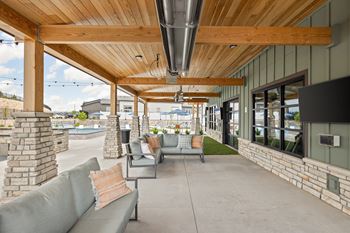 a covered patio with couches and chairs and a tv