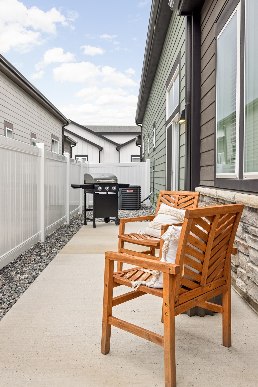 a patio with chairs and a grill on the side of a house