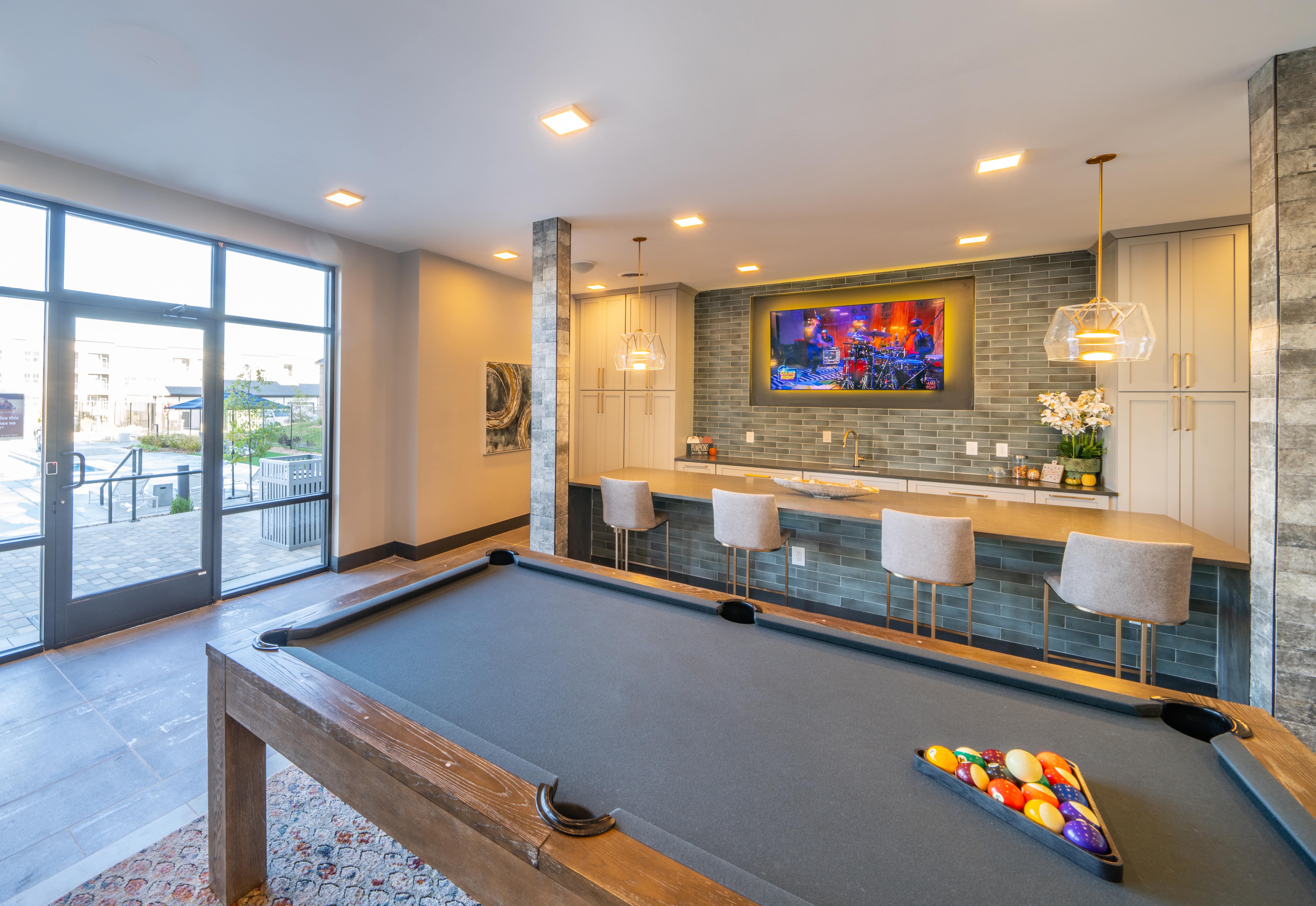 a pool table in a living room with a bar and a tv
