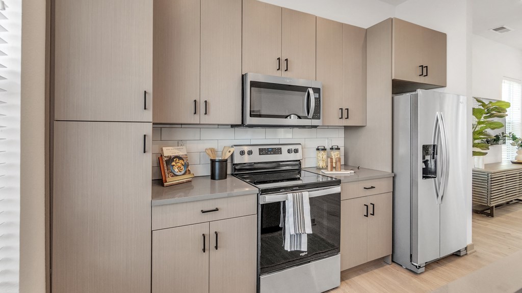 a kitchen with gray cabinets and stainless steel appliances at Slate at Fishers District, Indiana