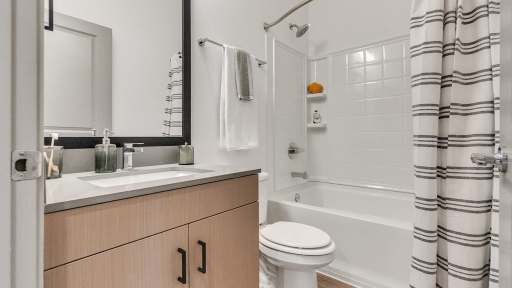 a bathroom with a white toilet next to a bathtub with a shower curtain at Slate at Fishers District, Fishers, IN, 46037