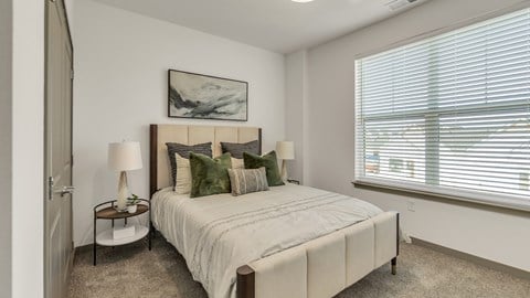 a bedroom with a large window and carpeted flooring at Slate at Fishers District, Indiana