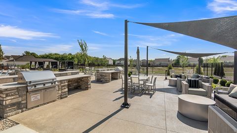 an outdoor patio with a grill and tables and chairs at Slate at Fishers District, Fishers