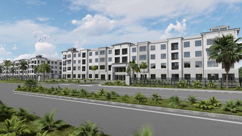 A modern building complex with a road in front and palm trees around.