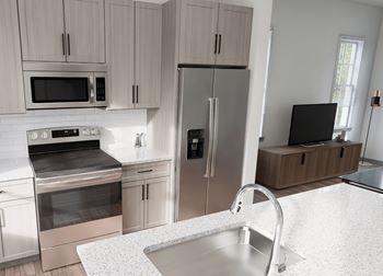 a kitchen with stainless steel appliances and white counter tops at The Hadley Luxury Apartments, North Port, Florida