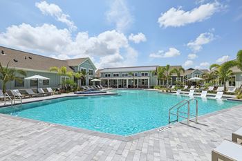A large swimming pool surrounded by lounge chairs and umbrellas.