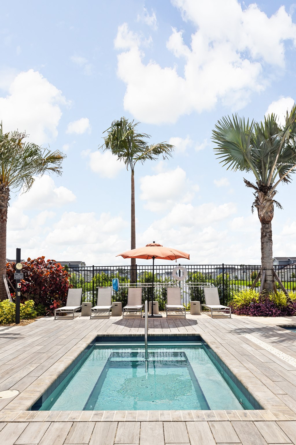 a pool with chairs and an umbrella on a deck with palm trees at The Sophia, Venice, FL, 34275