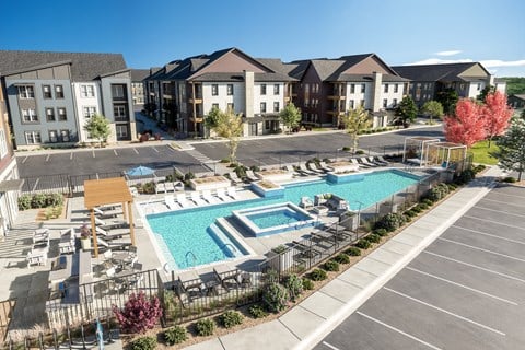 an aerial view of an apartment complex with a swimming pool and patio furniture