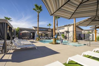 a pool with lounge chairs and umbrellas next to a building at Grandstone at Sunrise, Peoria, AZ