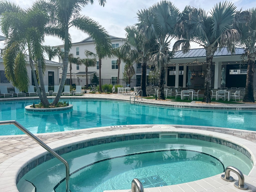 a large swimming pool with palm trees in front of a building at Drift, Daytona Beach, FL