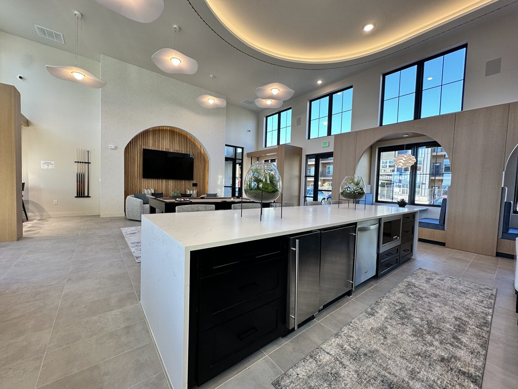 A modern kitchen with a curved island and a flat screen TV mounted on the wall.