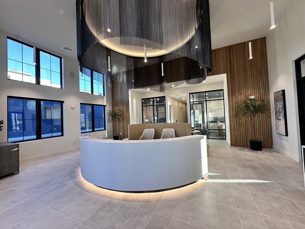 A reception area with a white circular desk and a hanging light fixture.
