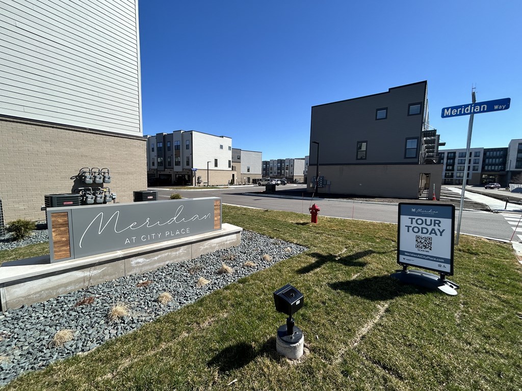 a sign sits in the grass in front of a building at Meridian at CityPlace, Minnesota
