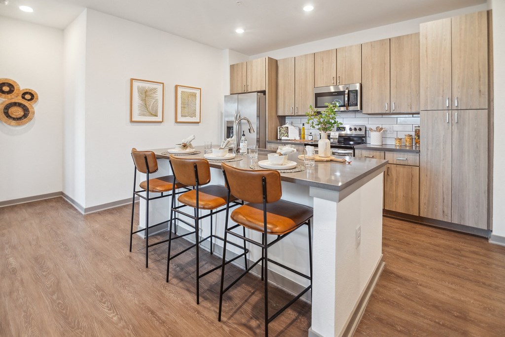 a kitchen with a island with four stools in front of it  at Palm Grove, Ellenton, FL, 34222