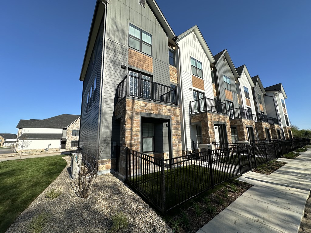 an exterior view of a row of apartments with a sidewalk and grass at The BLVD at Wilson Crossings, Wyoming, MI