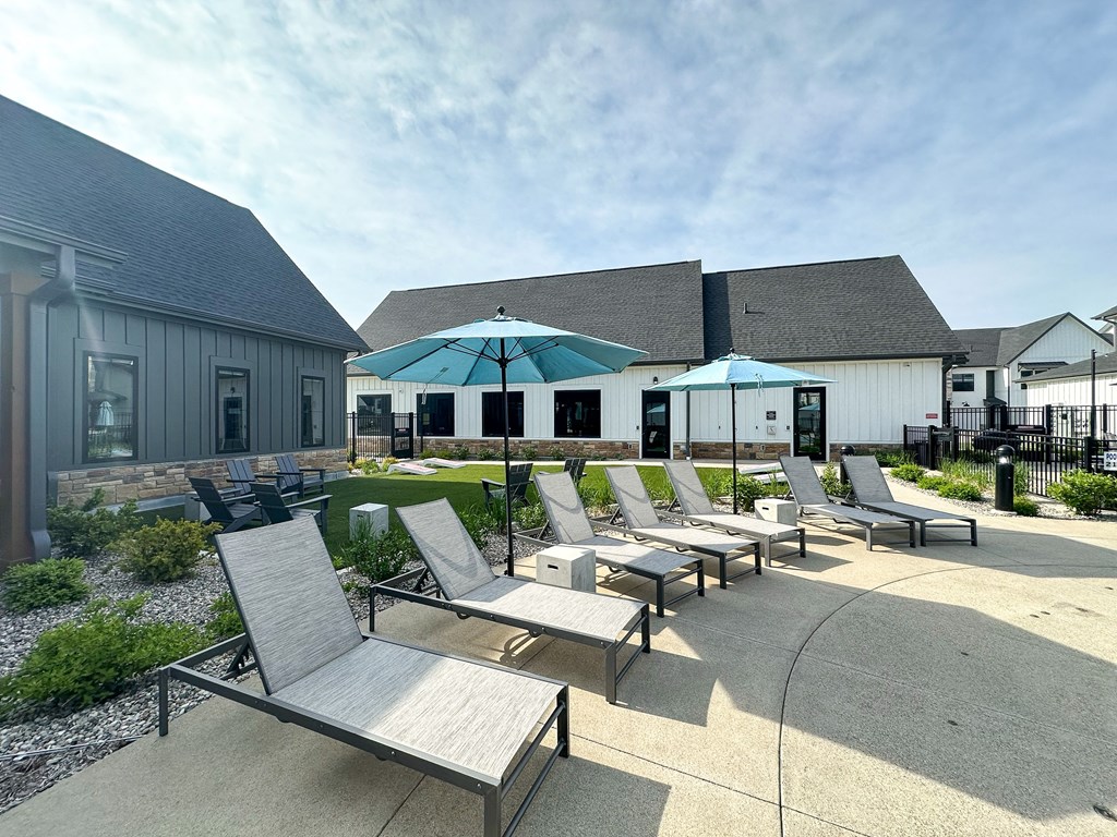 a patio with chairs and umbrellas in front of a building at The BLVD at Wilson Crossings, Wyoming Michigan