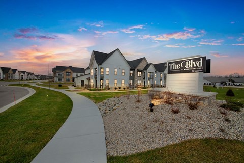 an exterior view of the residences at dusk with a sidewalk and grass