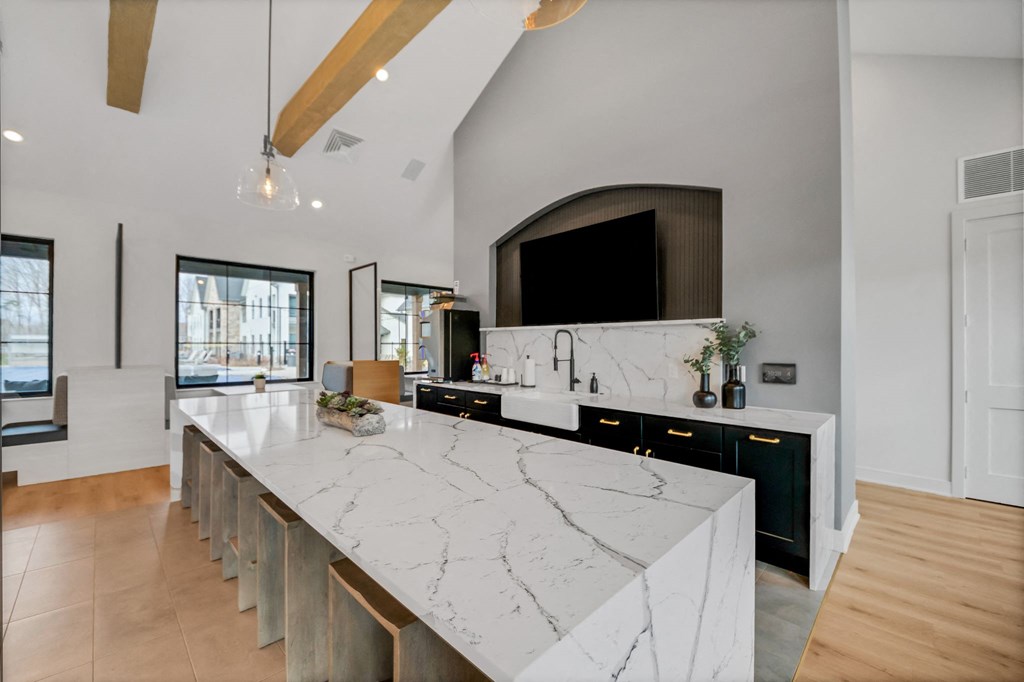 the kitchen has a large island with marble counter tops and a large tv at The BLVD at Wilson Crossings, Wyoming, 49418