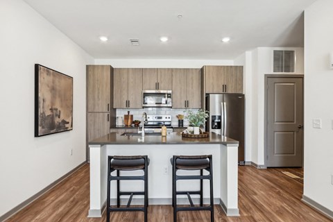 a kitchen with a large island with two stools and a stainless steel refrigeratorat Stella, San Tan Valley, 85143