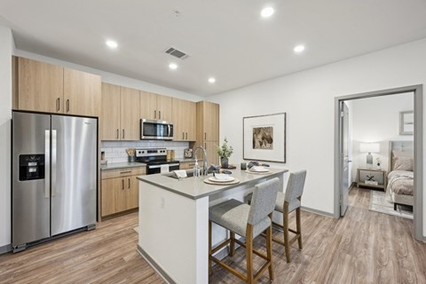 a kitchen with a large island and a stainless steel refrigerator a kitchen with a large island and a stainless steel refrigerator at The Garrison Luxury Apartment Homes, Colorado