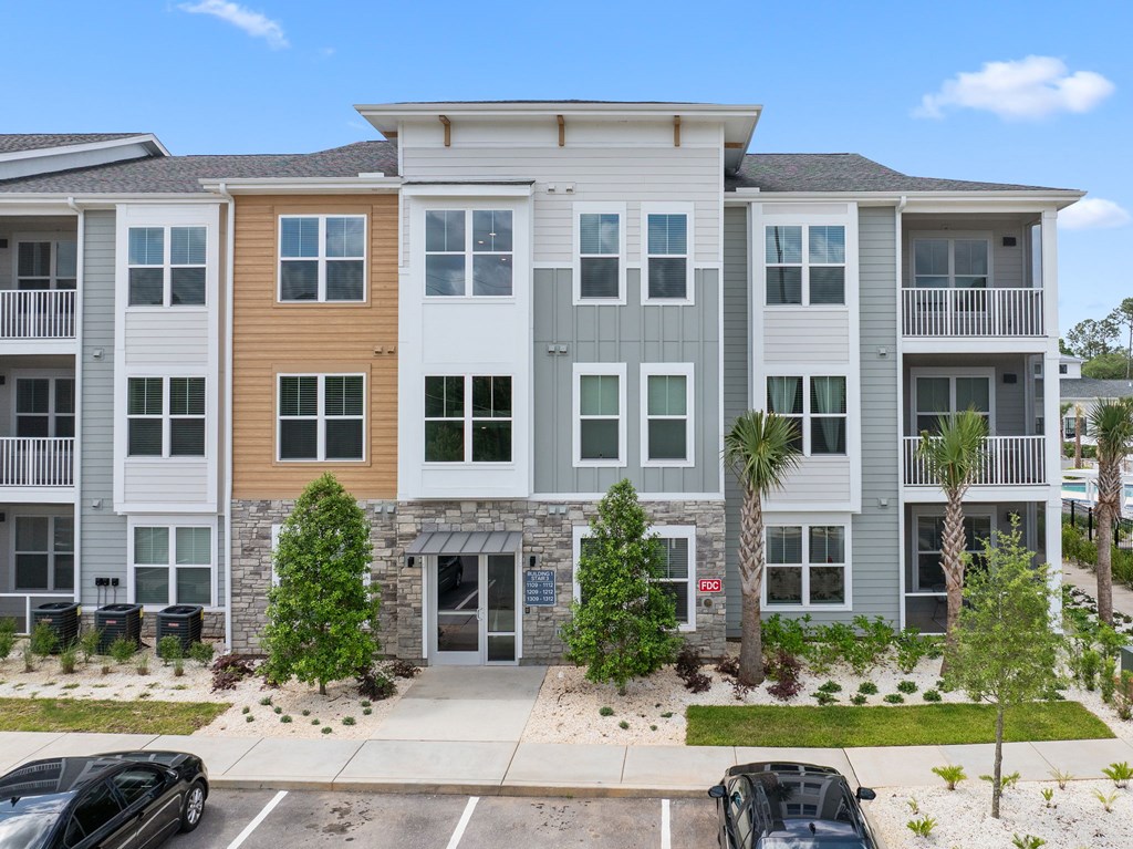 A multi-story apartment building with a parking lot in front.