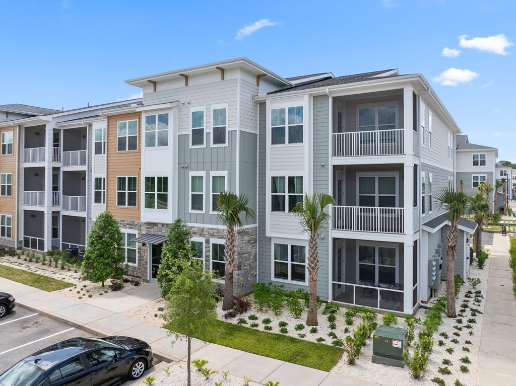 A black car is parked in front of a two-story apartment building.