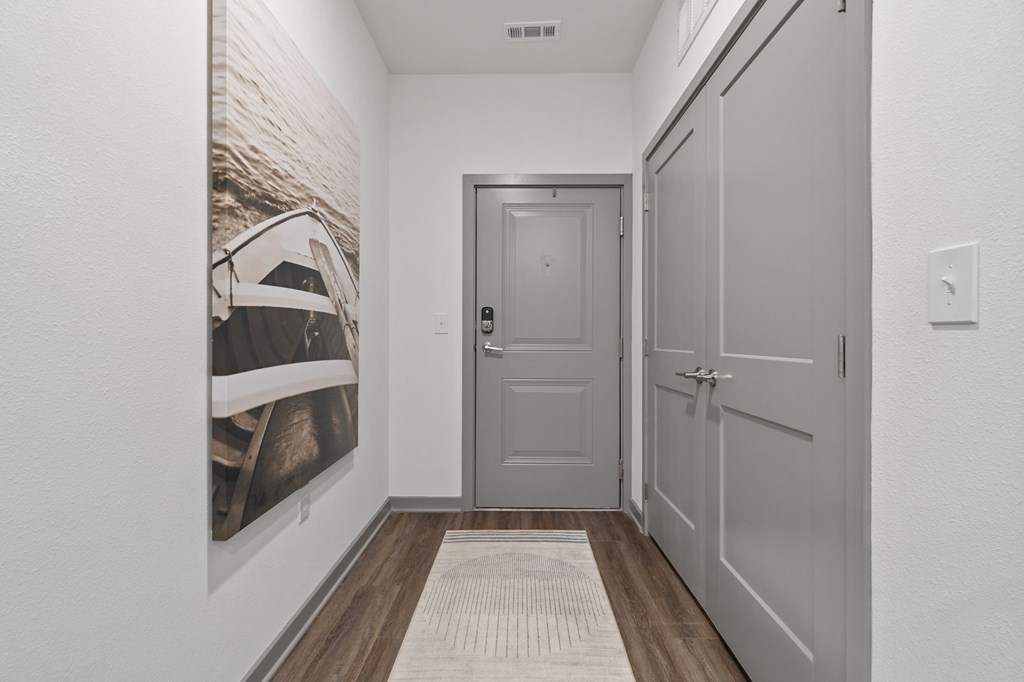 A hallway with a grey door and a framed picture of a boat on the wall.