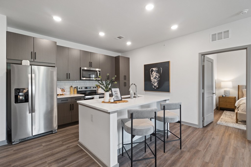 A modern kitchen with a refrigerator, microwave, oven, and sink.